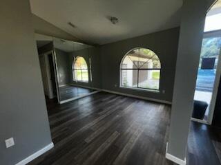 An empty room features dark wood-look flooring, gray walls, a large arched window, and mirrored doors — 108 Greentree Lane, FL 34797, FL