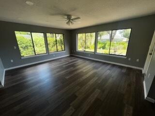 An empty room with dark wood-look flooring, gray walls, and large windows overlooking greenery — 108 Greentree Lane, FL 34797, FL