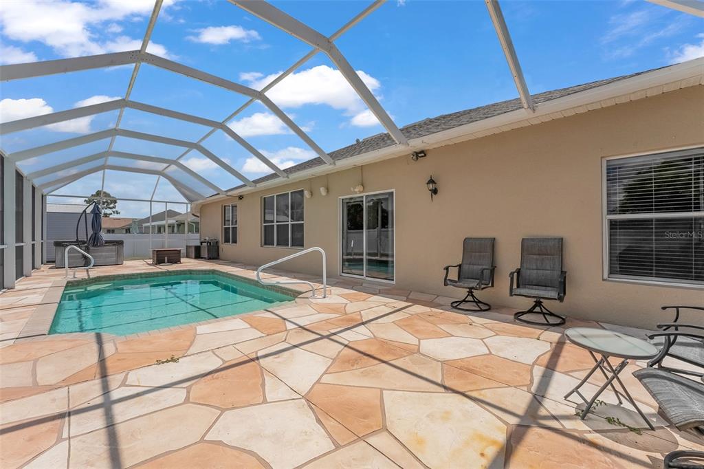 A screened-in patio features a swimming pool, stone-style pavers, and outdoor furniture — 1709 NW 15TH TERRACE, CAPE CORAL, FL