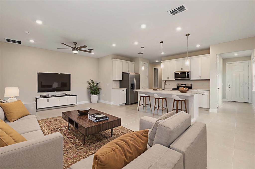 An open-concept kitchen and living area with light tile flooring and white cabinetry — 5811 SILVERSIDE PINE COURT, LAKEWOOD RANCH, FL
