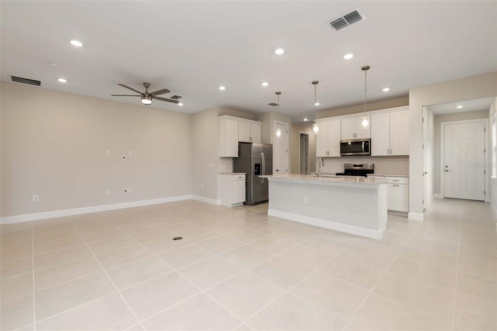 An open-concept living and dining area features a kitchen island, white cabinetry, and tile flooring — 5811 SILVERSIDE PINE COURT, LAKEWOOD RANCH, FL