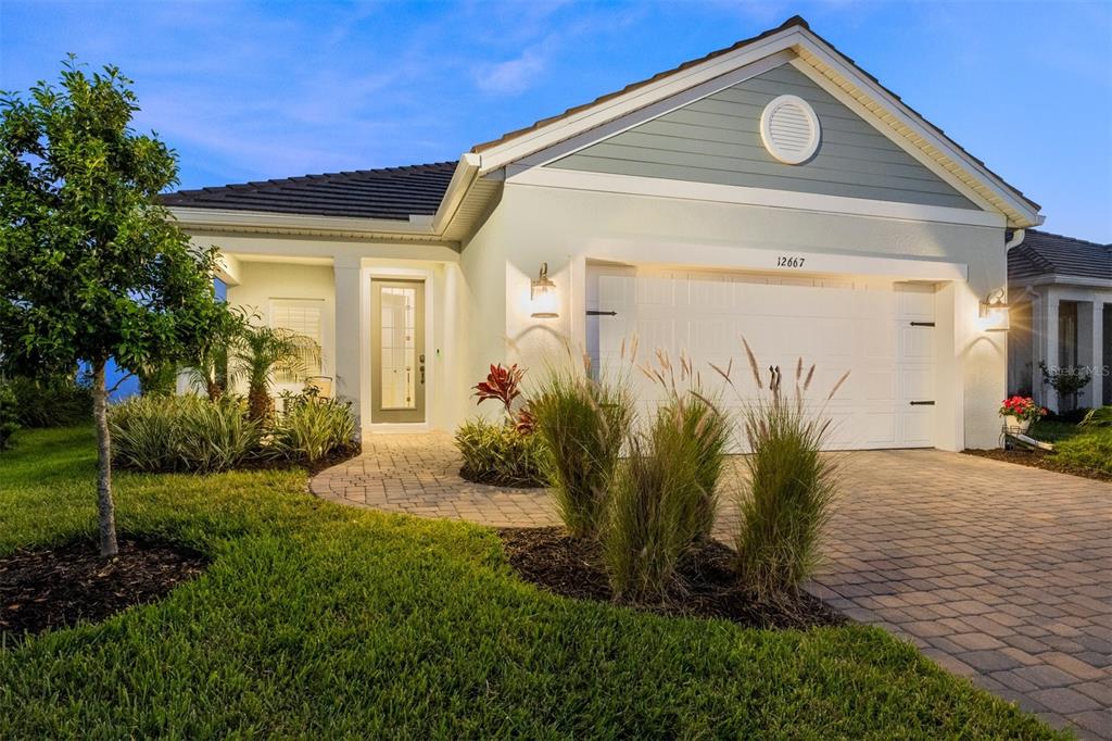 A single-story house with a white garage, light-colored siding, and a paved walkway — 12667 BROOKGREEN STREET, VENICE, FL