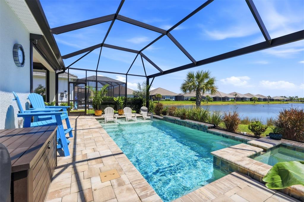A screened-in patio features a rectangular swimming pool, a hot tub, and lake views — 12667 BROOKGREEN STREET, VENICE, FL