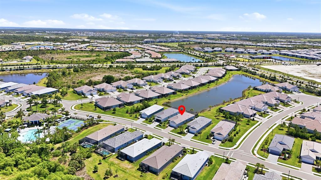 Aerial view of a residential neighborhood with houses, a lake, and community amenities — 12667 BROOKGREEN STREET, VENICE, FL