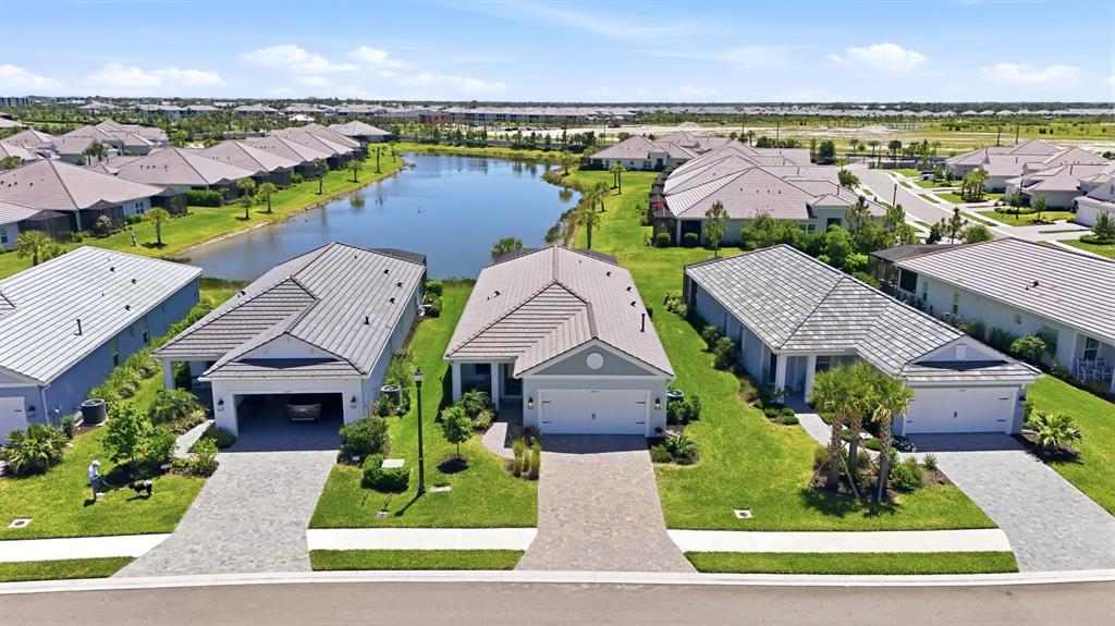 An aerial view shows a row of suburban houses with paved driveways facing a pond — 12667 BROOKGREEN STREET, VENICE, FL