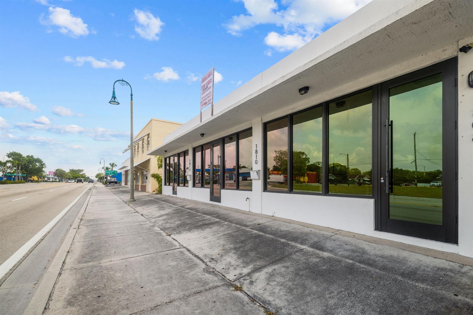 A street-level view of a commercial building exterior with large glass windows and doors — 1808/1810 N Dixie Highway, FL 33460, FL