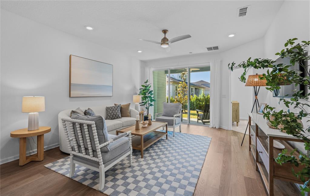 A bright living room features a sofa, two armchairs, a coffee table, and sliding glass doors — 227 MISTY HARBOR TRACE, PALM COAST, FL
