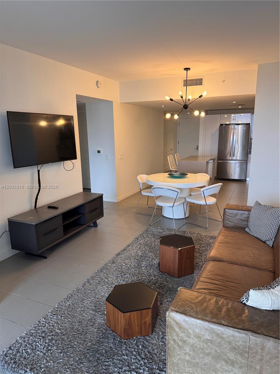 A living and dining area features a leather sofa, television, and a round dining table — 1600 NE 1st Ave # 2015, Miami FL 33132, MIAMI, FL