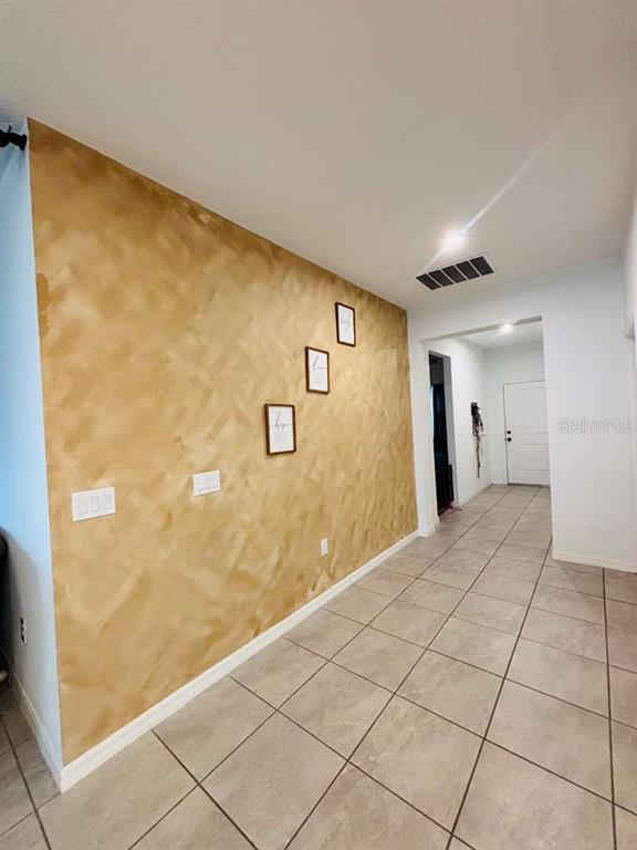 A hallway features a textured gold accent wall, tiled flooring, and three small framed pictures — 1051 PATRIOT LOOP, HAINES CITY, FL