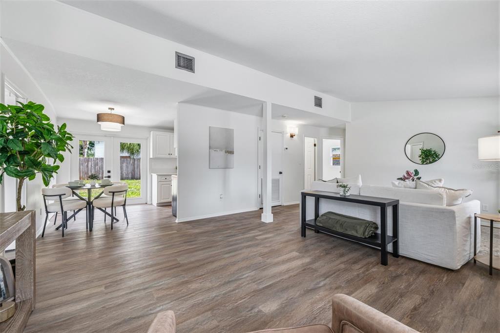 An open-concept living and dining area with wood-look flooring and white walls — 10408 VENTURA AVENUE, TAMPA, FL