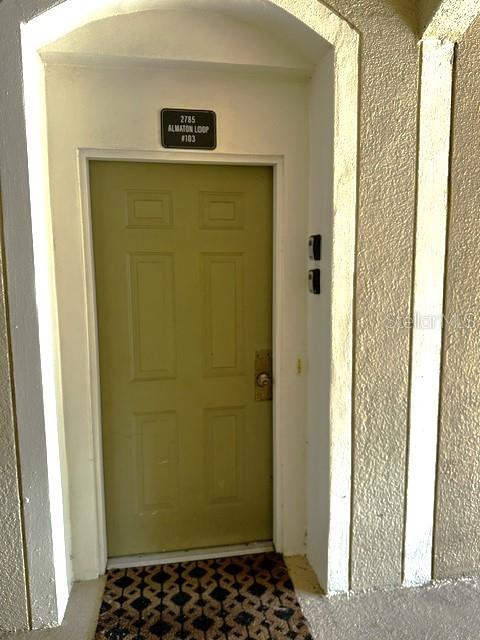 A green front door with a unit number sign is set in a stucco entryway — 2785 ALMATON LOOP UNIT 103, KISSIMMEE, FL