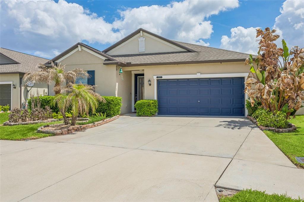 A single-story house with a beige exterior, blue garage door, and a concrete driveway — 21922 CREST MEADOW DRIVE, LAND O LAKES, FL