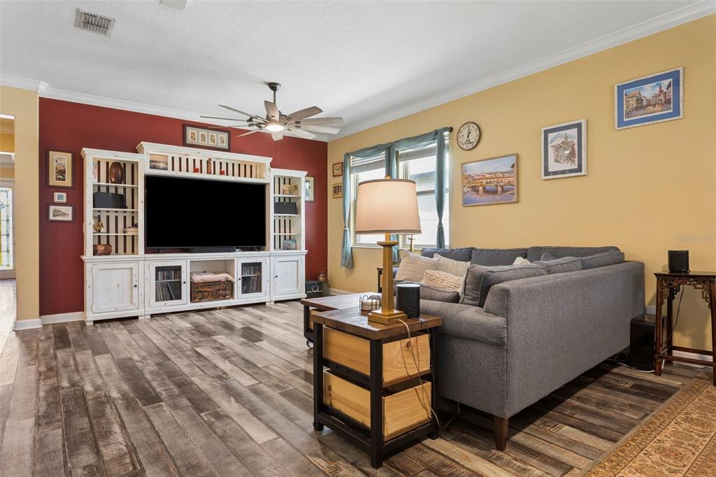 A living room features a large gray sectional sofa, a white media console, and wood-look flooring — 21922 CREST MEADOW DRIVE, LAND O LAKES, FL