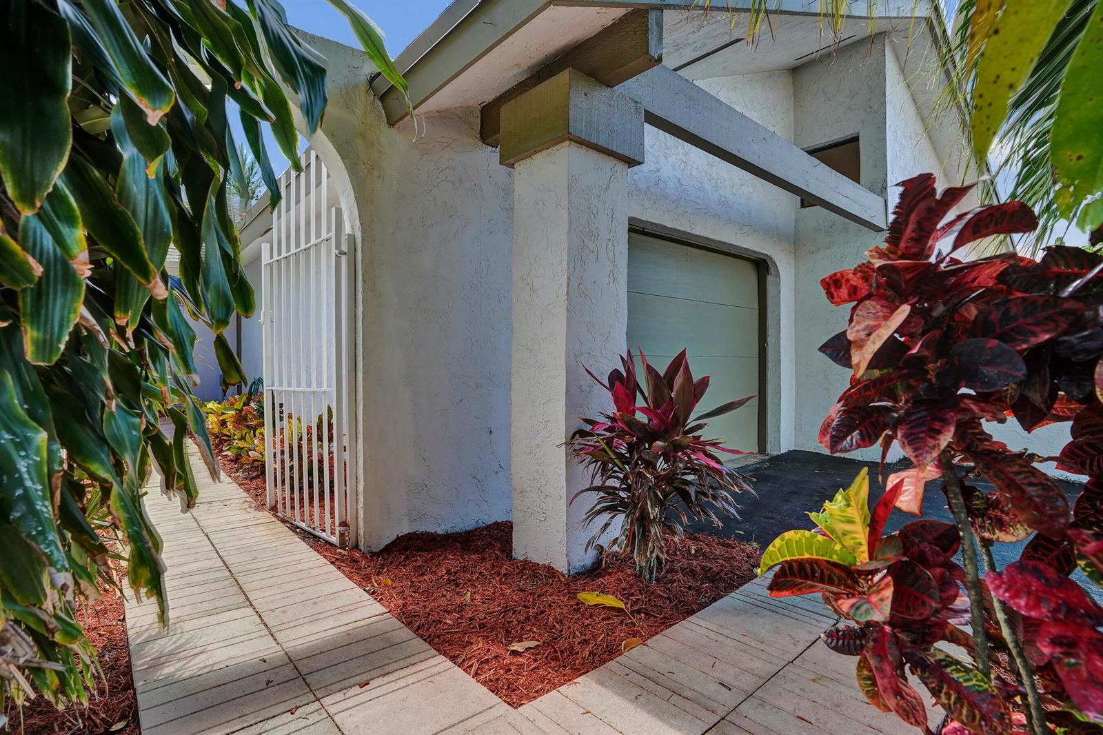 A white stucco house exterior features a metal gate, a garage, and tropical landscaping — 820 NW 21st Way # 820, Delray Beach FL 33445, DELRAY BEACH, FL