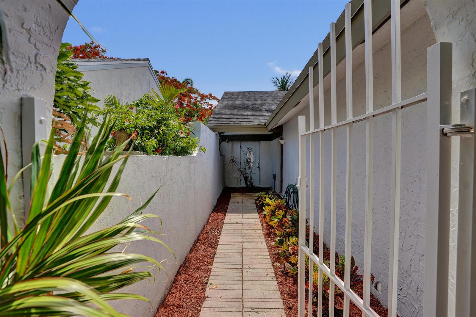 A narrow paved walkway leads to a white front door between two stucco walls — 820 NW 21st Way # 820, Delray Beach FL 33445, DELRAY BEACH, FL