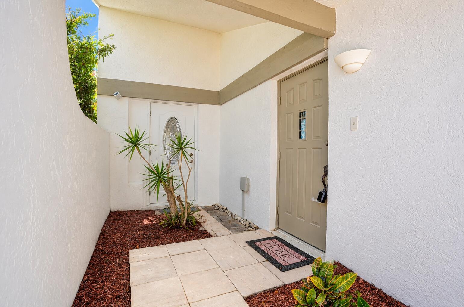 An exterior view of a home entrance featuring two doors, a walkway, and landscaping — 820 NW 21st Way # 820, Delray Beach FL 33445, DELRAY BEACH, FL