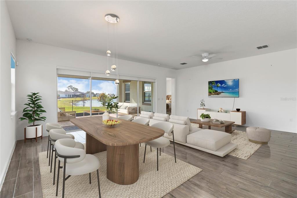 A bright open-concept living and dining area features wood-look tile flooring and a sliding glass door — 2709 GREENLANDS STREET, ST CLOUD, FL