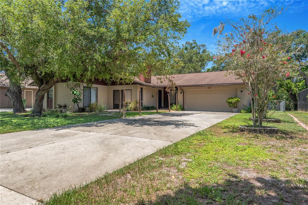 A single-story house with a concrete driveway, a two-car garage, and large shade trees — 213 WHISPERING OAKS COURT, SARASOTA, FL