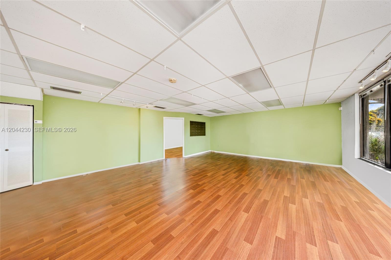 An empty room features light green walls, wood-look flooring, and a drop ceiling — 1235 SW 22nd St, Miami FL 33145, MIAMI, FL