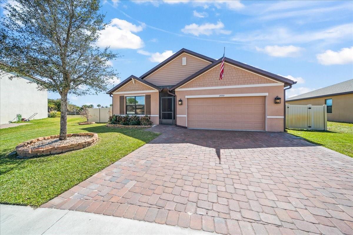 A single-story house with a tan stucco exterior, a paved driveway, and a front lawn — 7499 Tourmaline, Grant Valkaria FL 32949, GRANT VALKARIA, FL