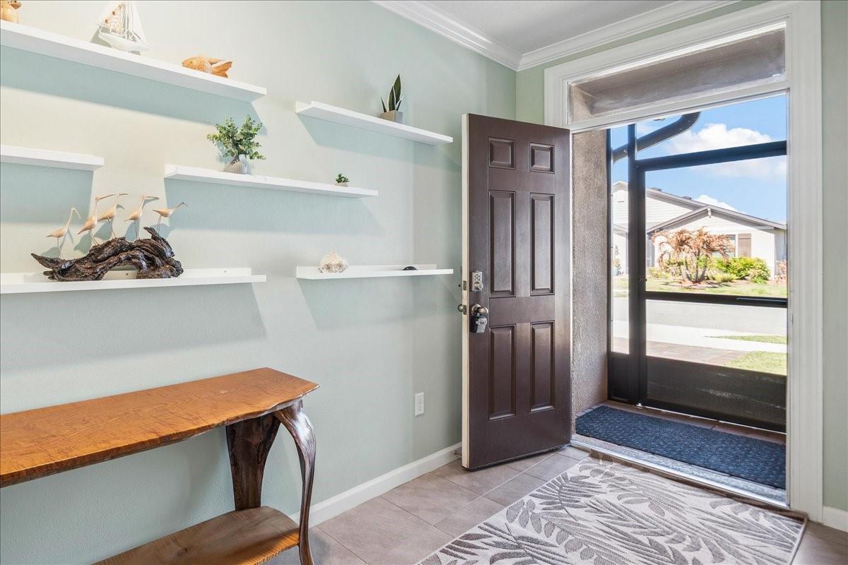 An entryway features light blue walls, floating shelves, a wooden console table, and an open door — 7499 Tourmaline, Grant Valkaria FL 32949, GRANT VALKARIA, FL