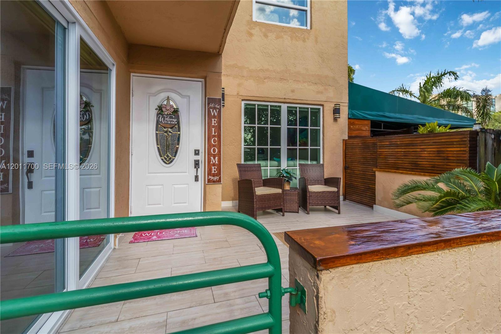 A patio features two wicker chairs, a welcome sign, and a green metal gate — 11880 SW 19th Ln # 165, Miami FL 33175, MIAMI, FL