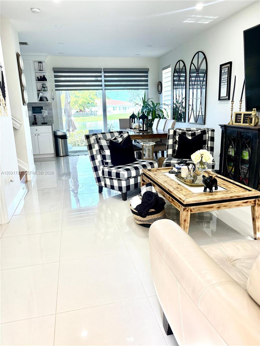 A living and dining area features tiled floors, buffalo check chairs, and a water view — PEMBROKE PINES, FL