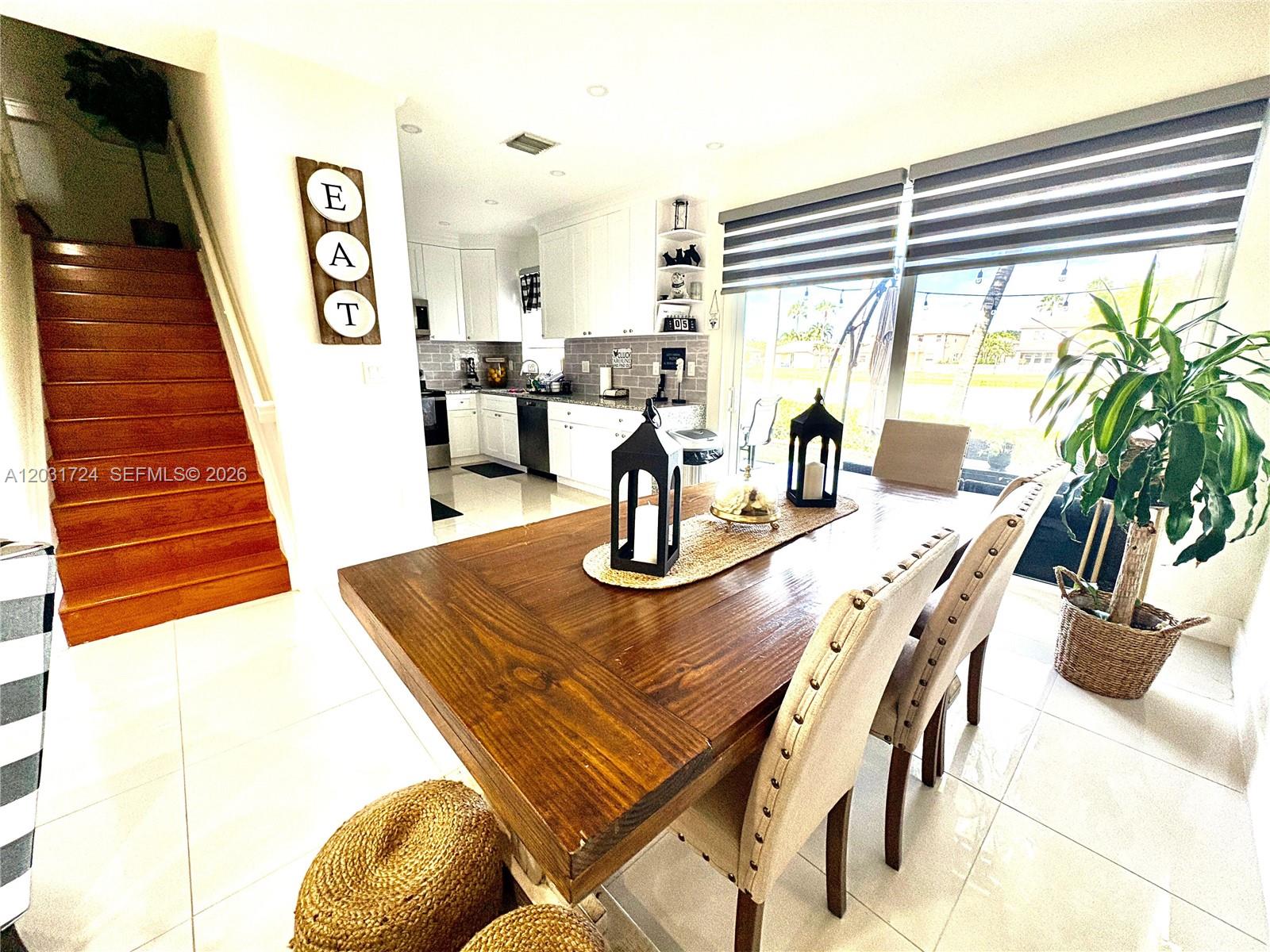 A dining area with a wooden table and chairs sits adjacent to a white kitchen — PEMBROKE PINES, FL