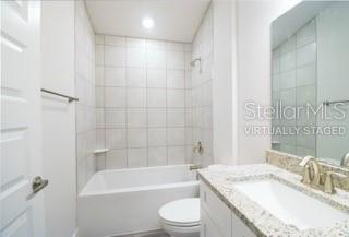 A bathroom features a white vanity with a stone countertop, a toilet, and a tiled tub — 1827 N ROBERTS TRAIL, BELL, FL