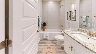 A bathroom features a white vanity, a bathtub with tiled walls, and light wood flooring — 1827 N ROBERTS TRAIL, BELL, FL