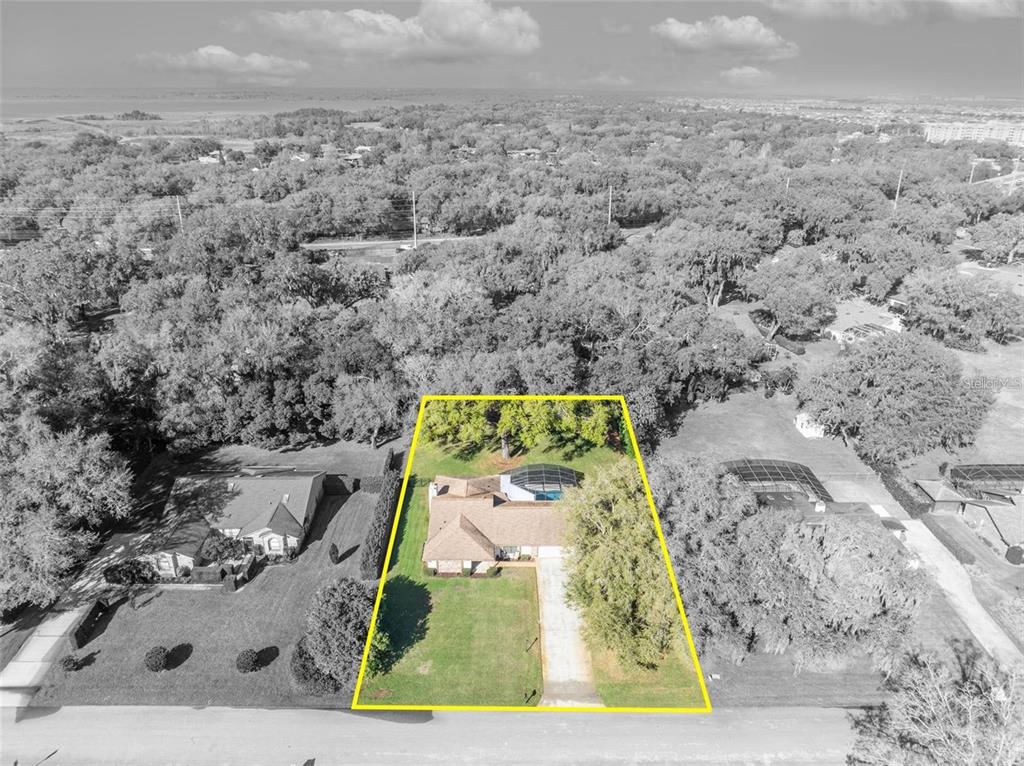 An aerial view shows a single-story house with a pool and screened enclosure on a lot — 3158 WHISPER WIND DRIVE, ST CLOUD, FL