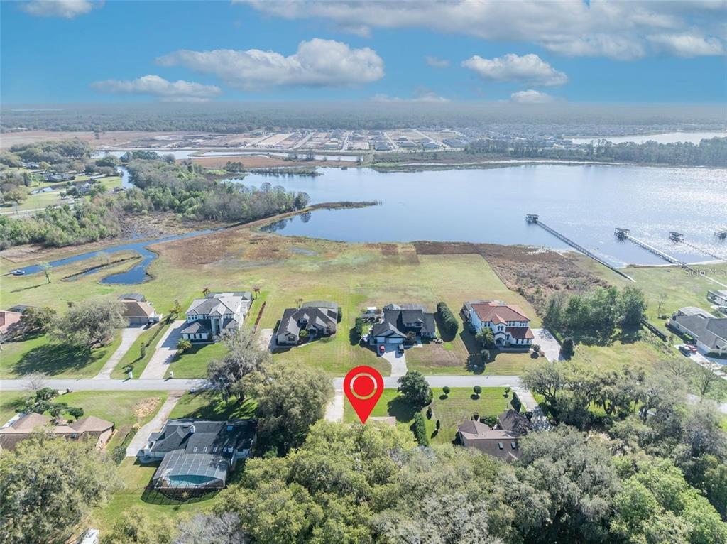 An aerial view shows a residential property with a red location pin near a lake — 3158 WHISPER WIND DRIVE, ST CLOUD, FL