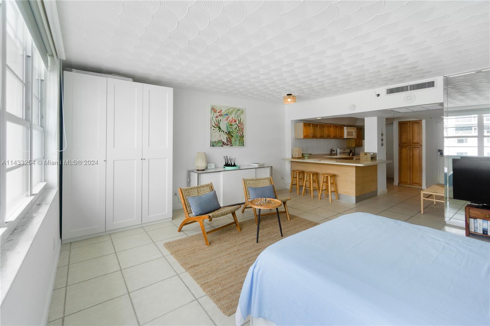 A studio apartment features a kitchen with a breakfast bar, seating area, and white cabinetry — 100 Lincoln Rd # 1039, Miami Beach FL 33139, MIAMI BEACH, FL