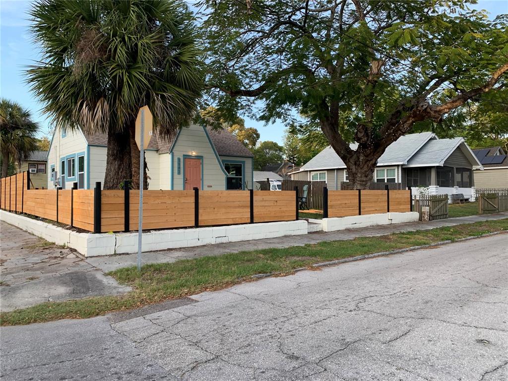 A street-level view shows two houses with a wooden fence and a white masonry wall — 1147 JAMES AVENUE S, ST PETERSBURG, FL