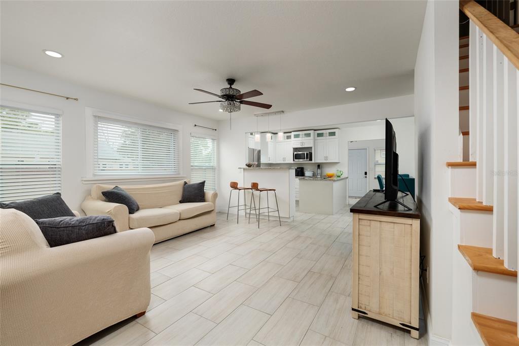 An open-concept living room and kitchen featuring light tile floors and white cabinetry — 1147 JAMES AVENUE S, ST PETERSBURG, FL