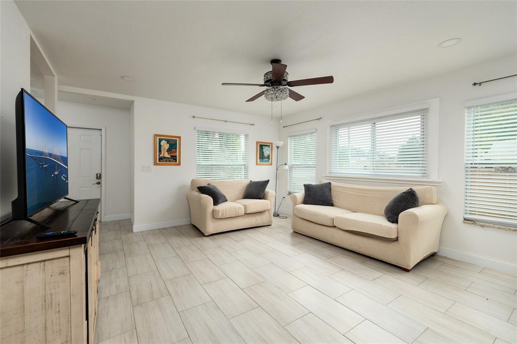 A living room features light tile flooring, two beige sofas, and a ceiling fan — 1147 JAMES AVENUE S, ST PETERSBURG, FL