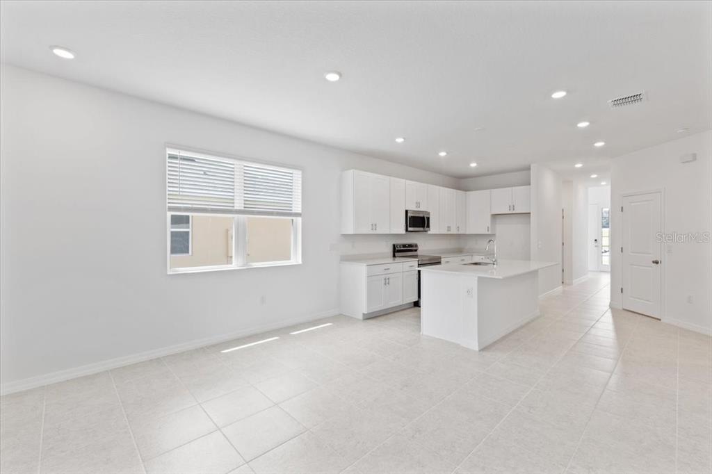 A bright kitchen features white cabinets, a central island, and light-colored tile flooring — 1198 ATLANTIC AVENUE, FRUITLAND PARK, FL