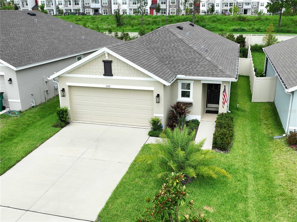 An aerial view of a single-story house with a two-car garage and a front lawn — 7737 SAIL CLOVER LANE, ZEPHYRHILLS, FL