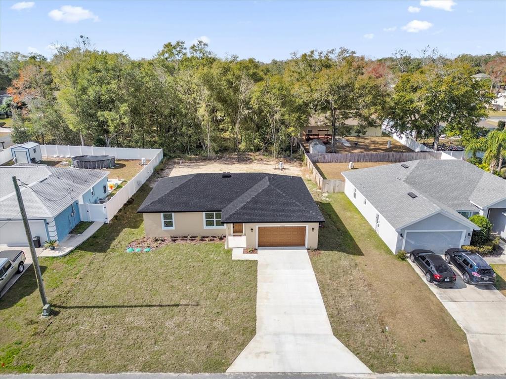 An aerial view shows a single-story house with a black roof and a concrete driveway — 16440 SE 87TH COURT, SUMMERFIELD, FL