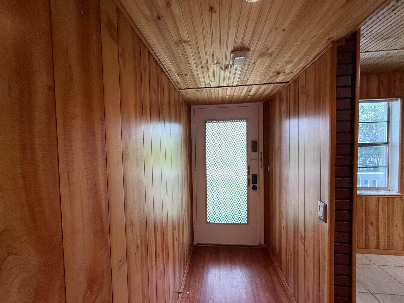 A narrow entryway features wood-paneled walls, a wood-plank ceiling, and a white storm door — 3776 Inverrary Boulevard # 204r, Lauderhill FL 33319, LAUDERHILL, FL