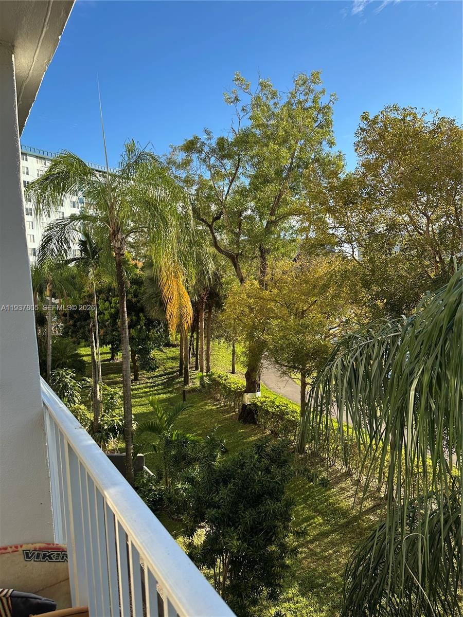 A view from a balcony overlooking a grassy area with various trees and a building — 3850 Washington St # 314, Hollywood FL 33021, HOLLYWOOD, FL