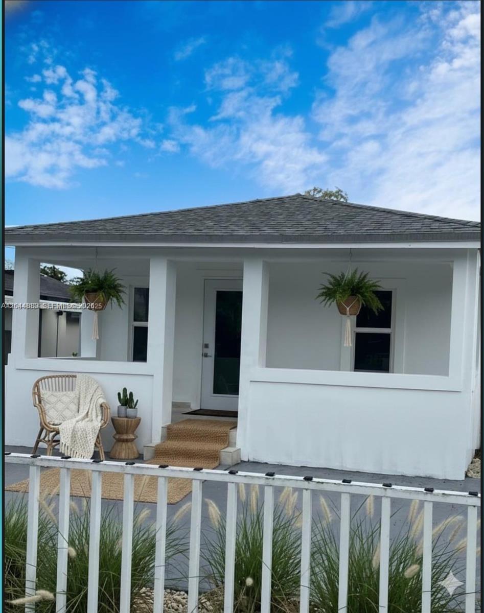 A white house with a covered front porch, hanging plants, and a small rattan chair — 81 NW 44th St, Miami FL 33127, MIAMI, FL