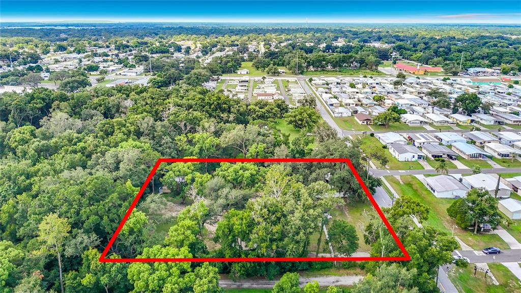 An aerial view shows a rectangular wooded lot outlined in red near a residential neighborhood — 6708 16TH STREET, ZEPHYRHILLS, FL