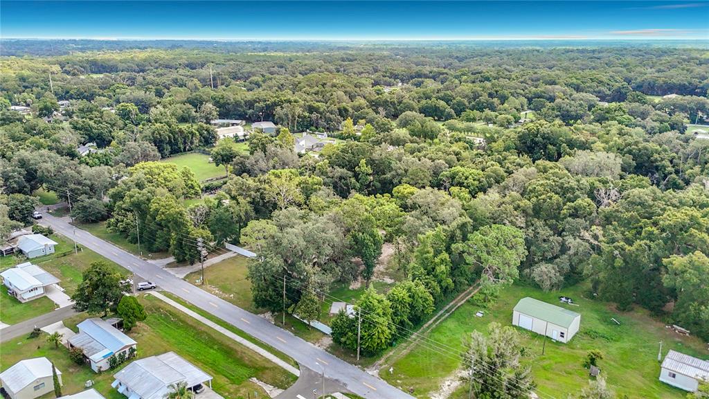 An aerial view shows a rural road lined with houses, trees, and a detached garage — 6708 16TH STREET, ZEPHYRHILLS, FL