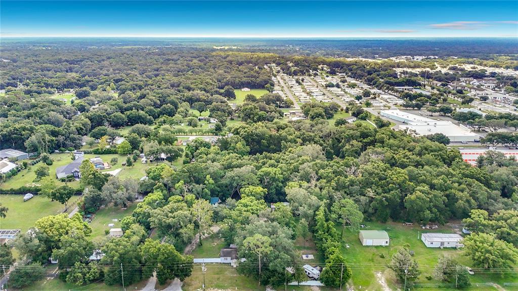 An aerial view shows a rural property with trees, small buildings, and a nearby neighborhood — 6708 16TH STREET, ZEPHYRHILLS, FL
