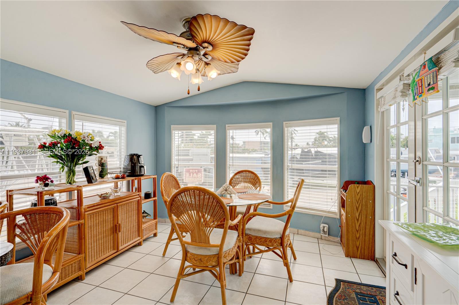 A sunroom features blue walls, tile flooring, a palm-leaf ceiling fan, and wicker dining furniture — 65821 Overseas Highway # 98, Long Key FL 33001, LONG KEY, FL
