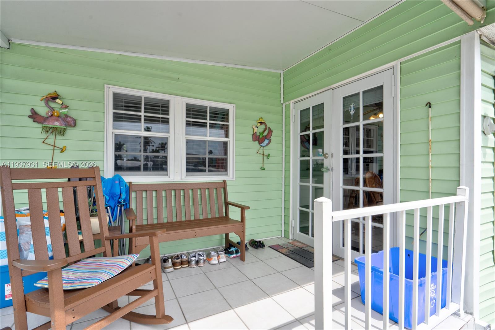 A covered porch features light green siding, a wooden bench, a rocking chair, and French doors — 65821 Overseas Highway # 98, Long Key FL 33001, LONG KEY, FL