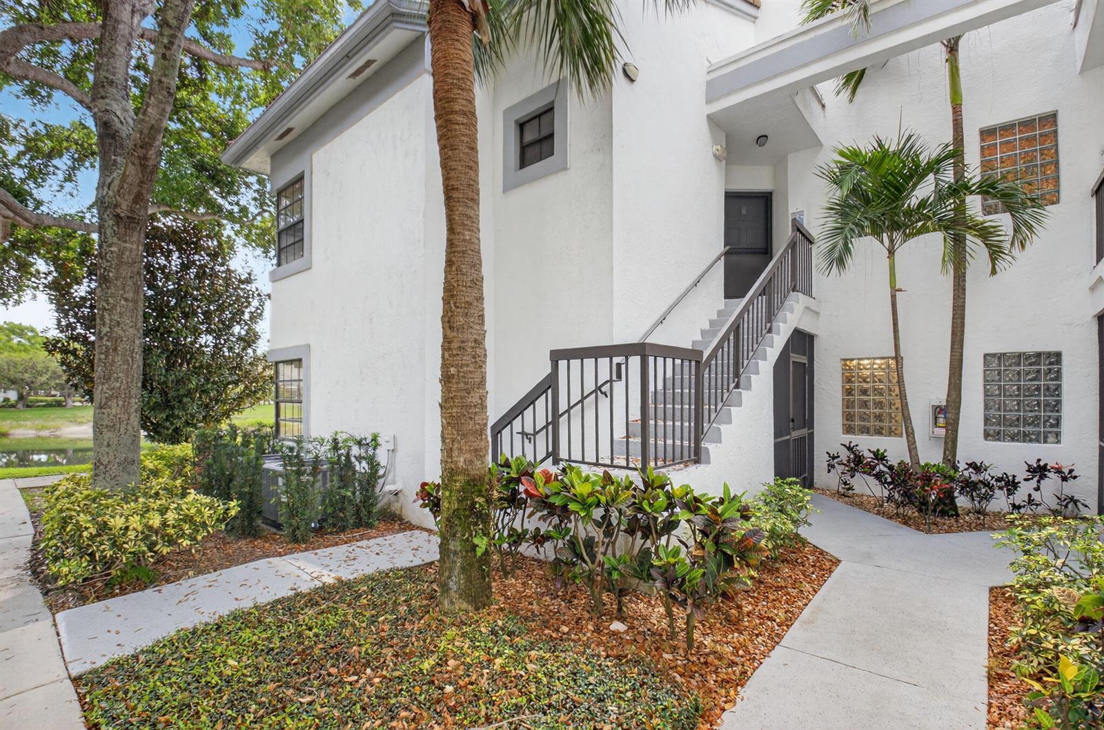A two-story white stucco building features an exterior staircase leading to an upper-level entrance — 5415 Verona Drive # F, Boynton Beach FL 33437, BOYNTON BEACH, FL
