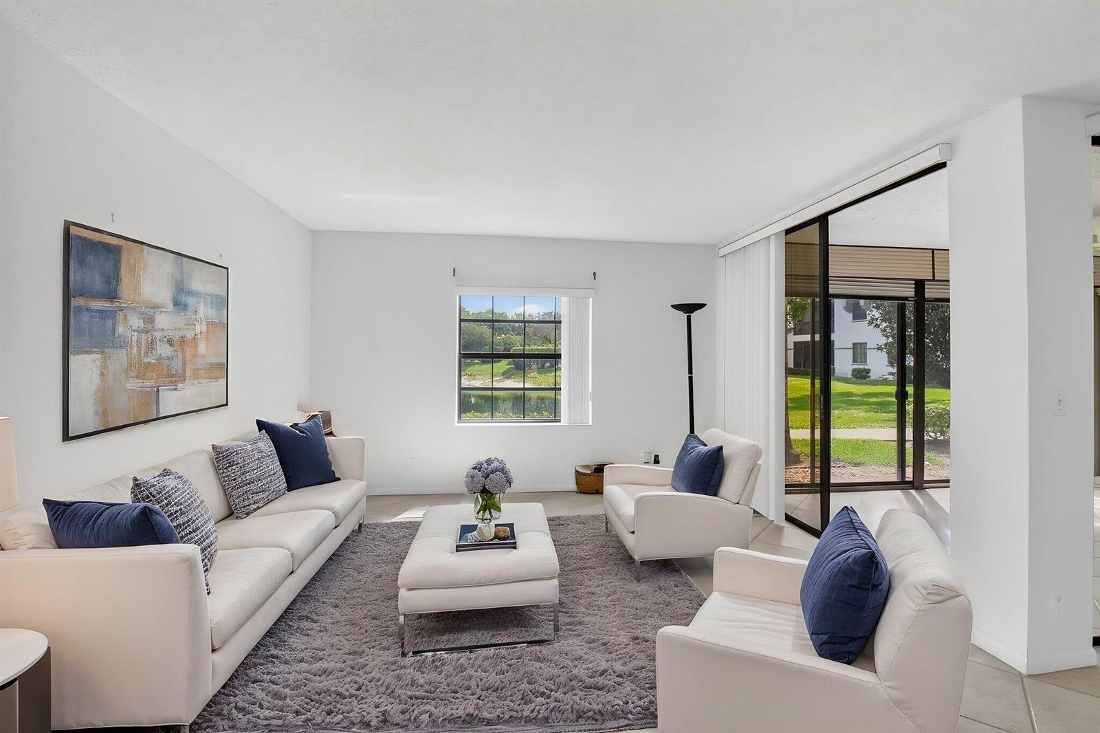 A bright living room features white furniture, a gray area rug, and a lake view — 5415 Verona Drive # F, Boynton Beach FL 33437, BOYNTON BEACH, FL