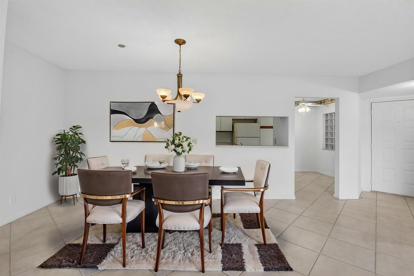 A dining room features a dark table, upholstered chairs, a chandelier, and a patterned rug — 5415 Verona Drive # F, Boynton Beach FL 33437, BOYNTON BEACH, FL